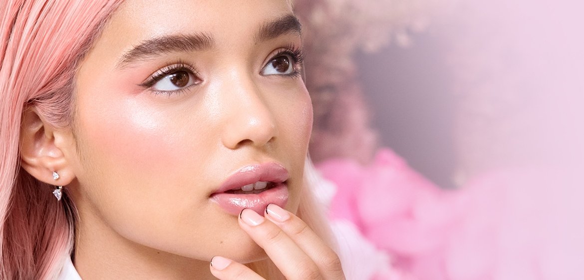 Eine junge Frau mit langen rosa gefärbten Haaren und Make-up schaut intereesiert